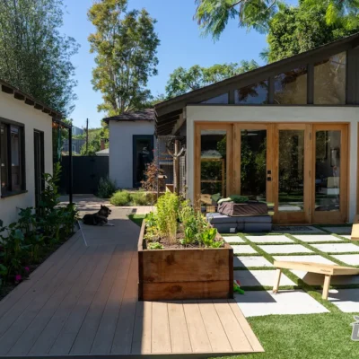 Renovated backyard with raised garden bed, modern home extension, and sliding glass doors by Ground Up Builders