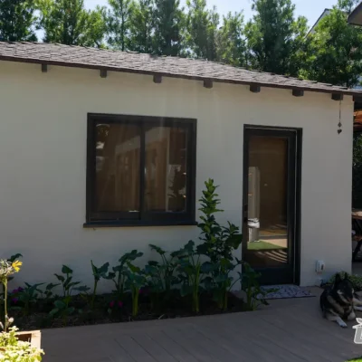 Backyard renovation with garden landscaping, modern walkway, and dog resting on deck by Ground Up Builders