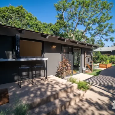 Backyard renovation with outdoor bar seating, modern walkway, and landscaped garden beds by Ground Up Builders