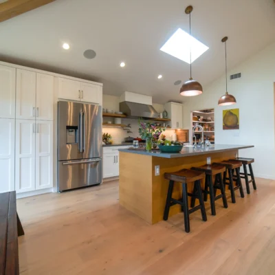 Spacious kitchen with white and light wood shaker cabinets, a large island, and stainless steel appliances.