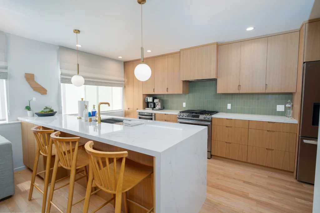 Light wood shaker cabinets and white countertops in a modern kitchen with a large island.