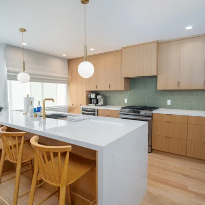 Light wood shaker cabinets and white countertops in a modern kitchen with a large island.