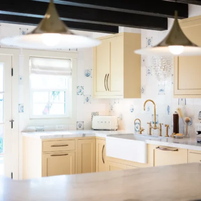 Cozy kitchen with cream-colored shaker cabinets, a white farmhouse sink, and industrial pendant lights.