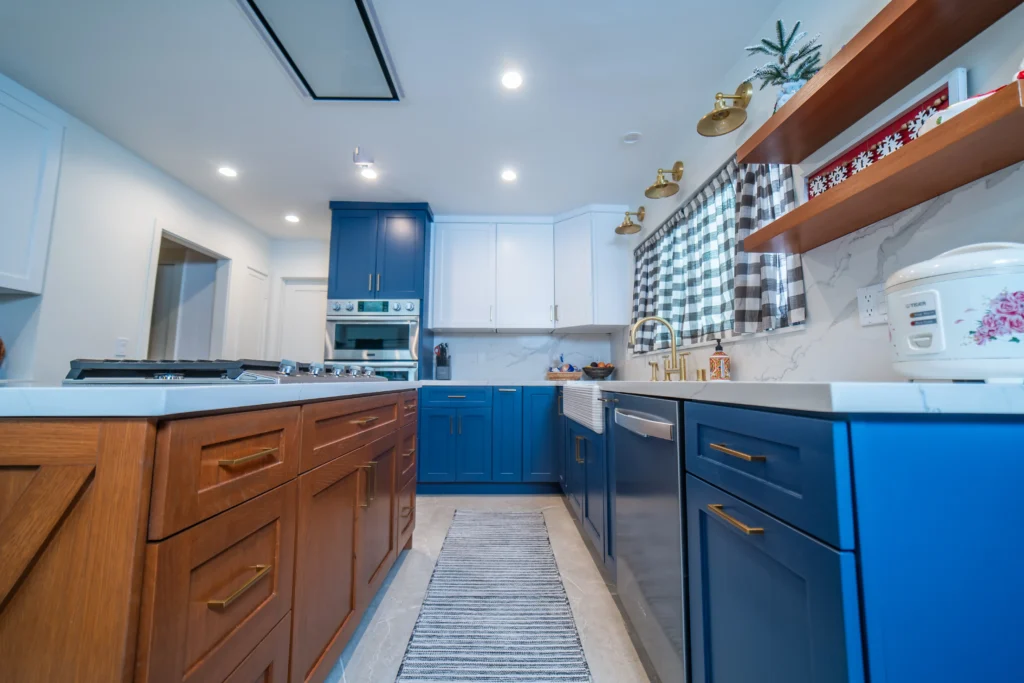 A spacious kitchen with blue lower cabinets, white upper cabinets, a wooden island, and a runner rug on the floor.