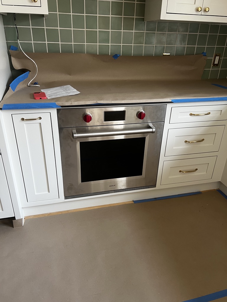 Kitchen with white cabinets, stainless steel oven, and protective paper during a remodel project in Echo Park, Los Angeles